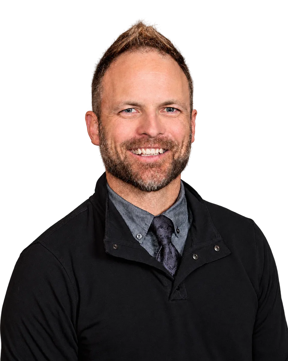Brady Baxter, smiling, in a black pullover over a gray shirt and tie